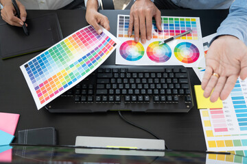 graphic designer team working on web design using color swatches editing artwork using tablet and a...