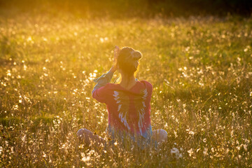 Woman meditating in a field during sunset hour