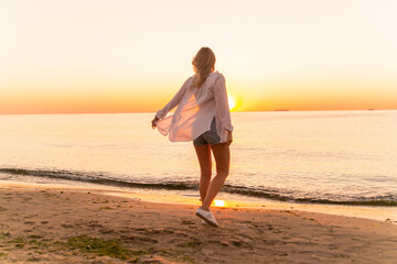 A slender girl in white clothes runs along the beach against the background of the sea. A sports girl runs along the embankment of the sea. Healthy woman on the beach