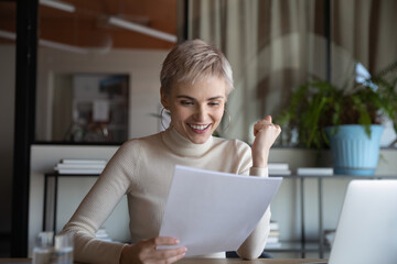 Excited young woman worker feel euphoric read good news in postal paperwork in modern office. Happy...