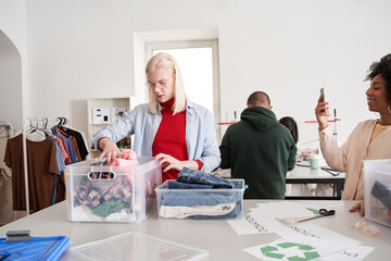 Woman shooting her male blonde colleague while he the sorting clothes