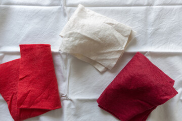 red and white felt fabric folded on white cotton material - photographed from above with ambient light 