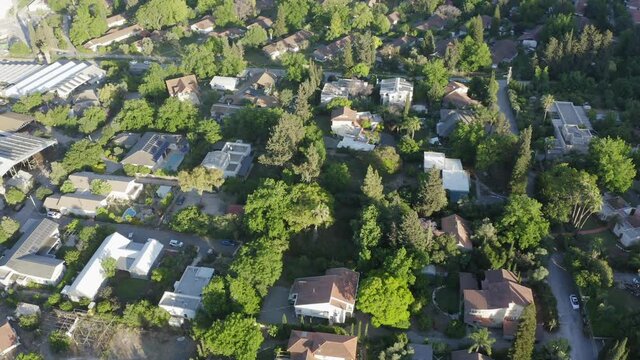 Aerial view of Yokneam Moshava houses surrounded by lush green forest trees.