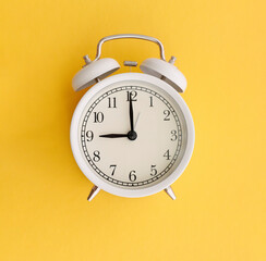 white table clock on yellow and pink background time