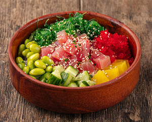Hawaiian tuna poke bowl with vegetables on wooden background