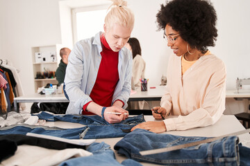 Colleagues cutting clothes while re sewing old products at the table