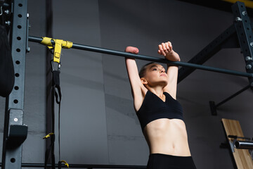Fototapeta premium strong-willed amputee woman working out on horizontal bar in gym