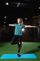 amputee sportswoman standing in one legged tree pose on fitness mat