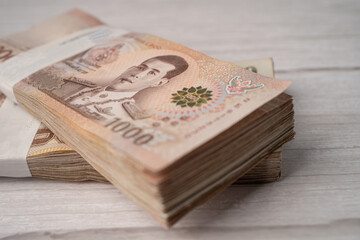 Stack of Thai baht banknotes on wooden background, business saving finance investment concept.