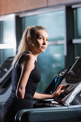 Obraz na płótnie Canvas disabled woman operating treadmill in sports center