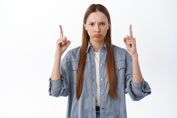 This is unfair. Upset or angry girl frowning, sulking and pointing fingers up at bad thing, being...