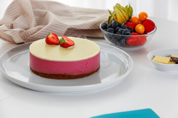 Decoration of vegetarian dessert, cake with berries. Ingredients: almond sponge biscuit, raspberry mousse, white chocolate ganache. The concept of vegan treats.