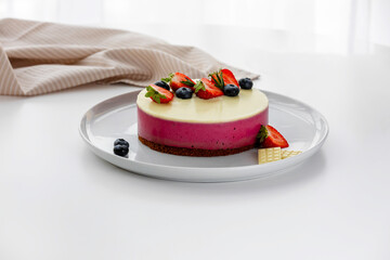 Decoration of vegetarian dessert, cake with berries. Ingredients: almond sponge biscuit, raspberry mousse, white chocolate ganache. The concept of vegan treats.