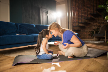 Woman meditating at living room with her daughter while bonding to each other