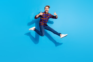 Fototapeta na wymiar Full length portrait of excited crazy guy show two thumbs up toothy smile rush isolated on blue color background