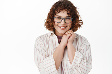 Obraz premium Close up of beautiful young woman in glasses looking coy and tender at camera, blushing, flirting or looking at something nice, standing romantic against white background