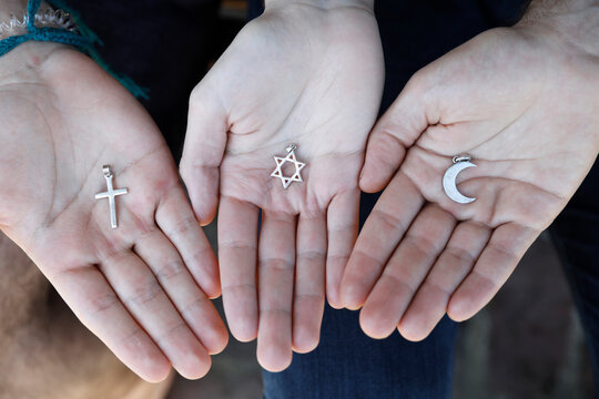 Young muslim, christian and jewish man showing religious symbols in France.