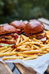 hamburgers and french fries on wooden table outdoor at a local cafe