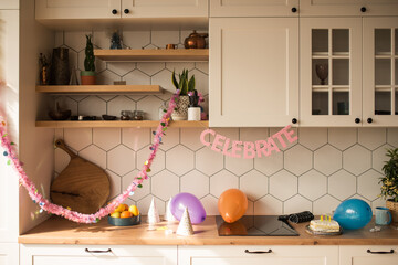 Party table with birthday cake with candles, balloons and colored decor