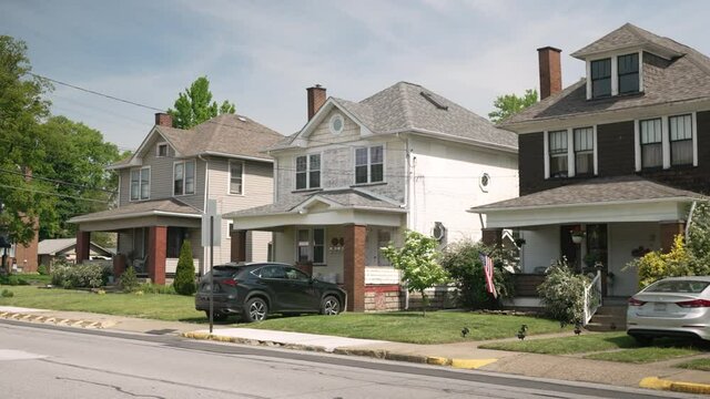 A summer view of typical middle class homes in the residential district of a small town. Traffic passes in front. Pittsburgh suburbs.  	