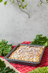 Kuchen mit Rhabarber und Streusel aus einem Blech auf einem Tisch aus hellem Holz