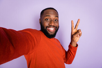 Fototapeta premium Self-portrait of attractive funny cheerful guy having fun showing v-sign isolated over violet purple pastel color background