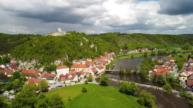 Drone rising high above the town and castle ruin of Kallm&uuml;nz in Bavaria, Germany on sunny day with dramatic clouds