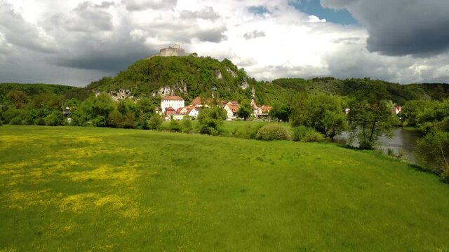 Drone rising high above the town and castle ruin of Kallm&uuml;nz in Bavaria, Germany on sunny day with dramatic clouds