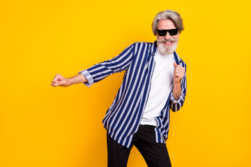 Photo of happy smiling funky funny mature man in sunglass relaxing dancing isolated on yellow color background