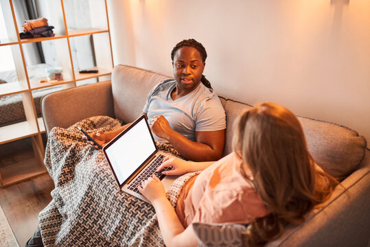 Man with dreadlocks looking at his caucasian wife and telling something to her