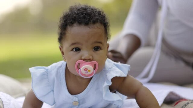 African American baby is sucking pacifier happy with family in garden. Love caring for children from mother. Development of young children in vision. Good health of children