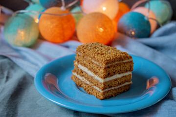 Honey cake on a blue plate with colorful lights