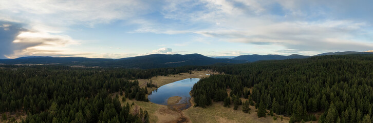 Fototapeta na wymiar Aerial Panoramic View of a Lake in the Canadian Landscape. Cloudy and Sunny Spring Sunset. Taken near Kamloops and Merritt, British Columbia, Canada.