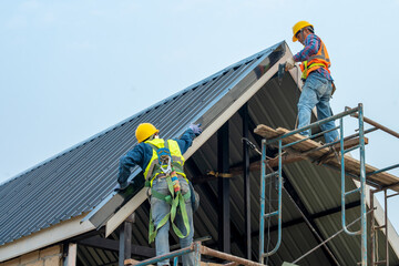 Roofer worker builder with hand drill installing new roof,Concept of residential building under construction.
