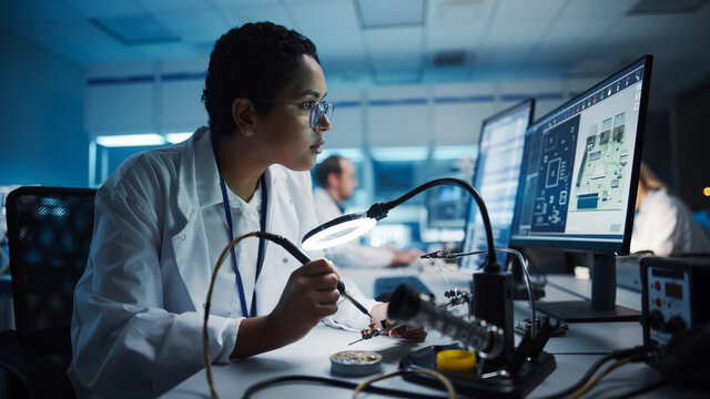 Modern Electronics Research, Development Facility: Black Female Engineer Does Computer Motherboard Soldering. Scientists Design Industrial PCB, Silicon Microchips, Semiconductors. Close-up Shot