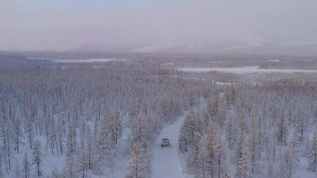 The six-wheel Trekol all-terrain vehicle rides through the snow-covered tundra in the sunset light
