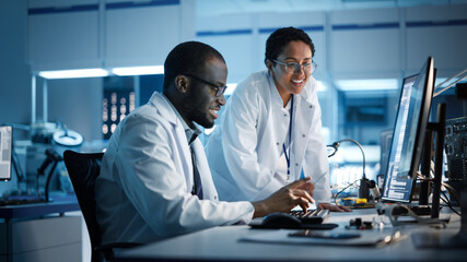 Electronics Research, Development Facility: Engineer Project Manager Talks With Scientist working on Computer. Diverse Team of Professionals Design Silicon Microchip, Semiconductors, Motherboard 