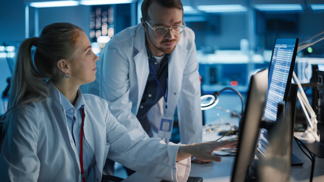 Electronics Research, Development Facility: Engineer Project Manager Consults Scientist working on Computer. Diverse Team of Professionals Design Silicon Microchip, Semiconductors, Motherboard 