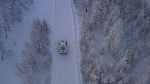 The six-wheel Trekol all-terrain vehicle rides through the snow-covered tundra in the sunset light
