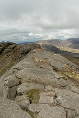 Woman with hat, pink jacket, standing on stones hiking, in Mourne Mountains Newry North Ireland