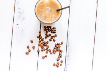 coffee break with cold iced latte and beans on white table background top view