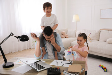 Overwhelmed man combining parenting and work at home