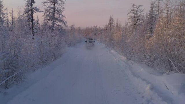The six-wheel Trekol all-terrain vehicle rides through the snow-covered tundra in the sunset light
