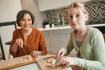 Grandmother and her ginger granddaughter chopping and looking at the camera