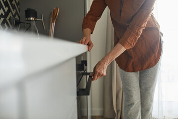 Woman opening the oven while preparing to the baking bagels for the breakfast