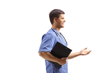 Male nurse in a blue uniform holding a clipboard and gesturing with hand