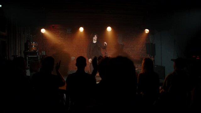 DOLLY Young Caucasian male comedian entering stage and greeting audience, performing his stand-up monologue inside a small venue. Shot with ARRI Alexa Mini LF with 2x anamorphic lens