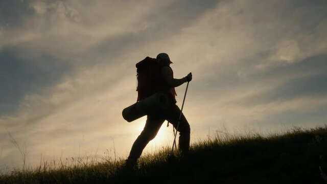 Silhouette of walking woman with backpack on the mountain
