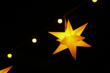 Star paper yellow lantern glows at night close-up - Powered by Adobe