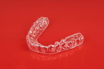Invisible orthodontics cosmetic brackets on red background. Tooth aligners, for beautiful smile.